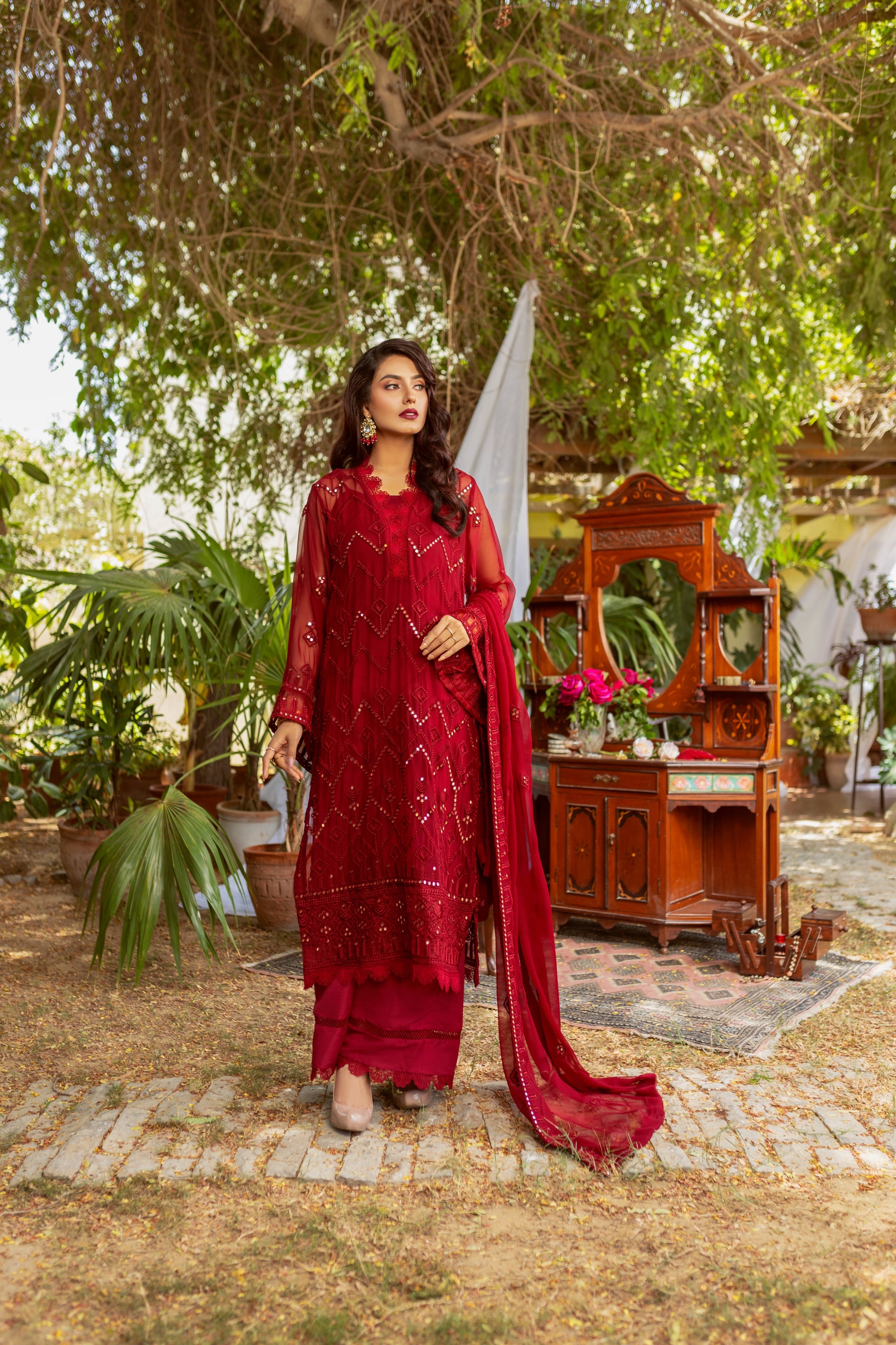 A female model wearing red chiffon suit with dupatta.