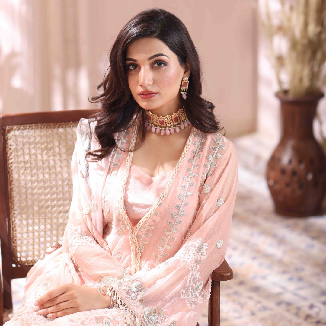 A girl is sitting on a chair wearing 3 Piece Embroidered Chiffon Suit.