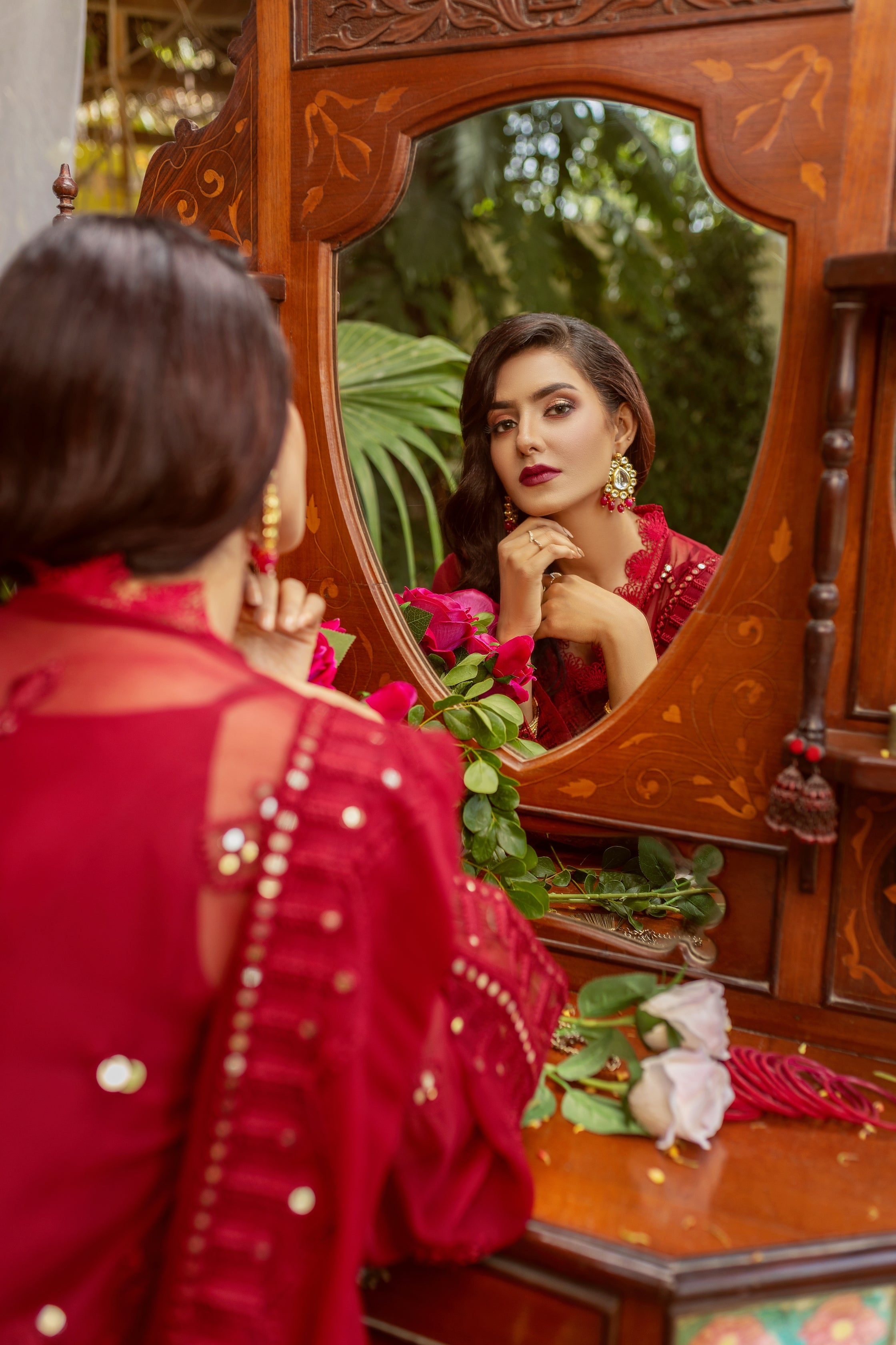 A girl wearing chiffon suit looking in mirror.