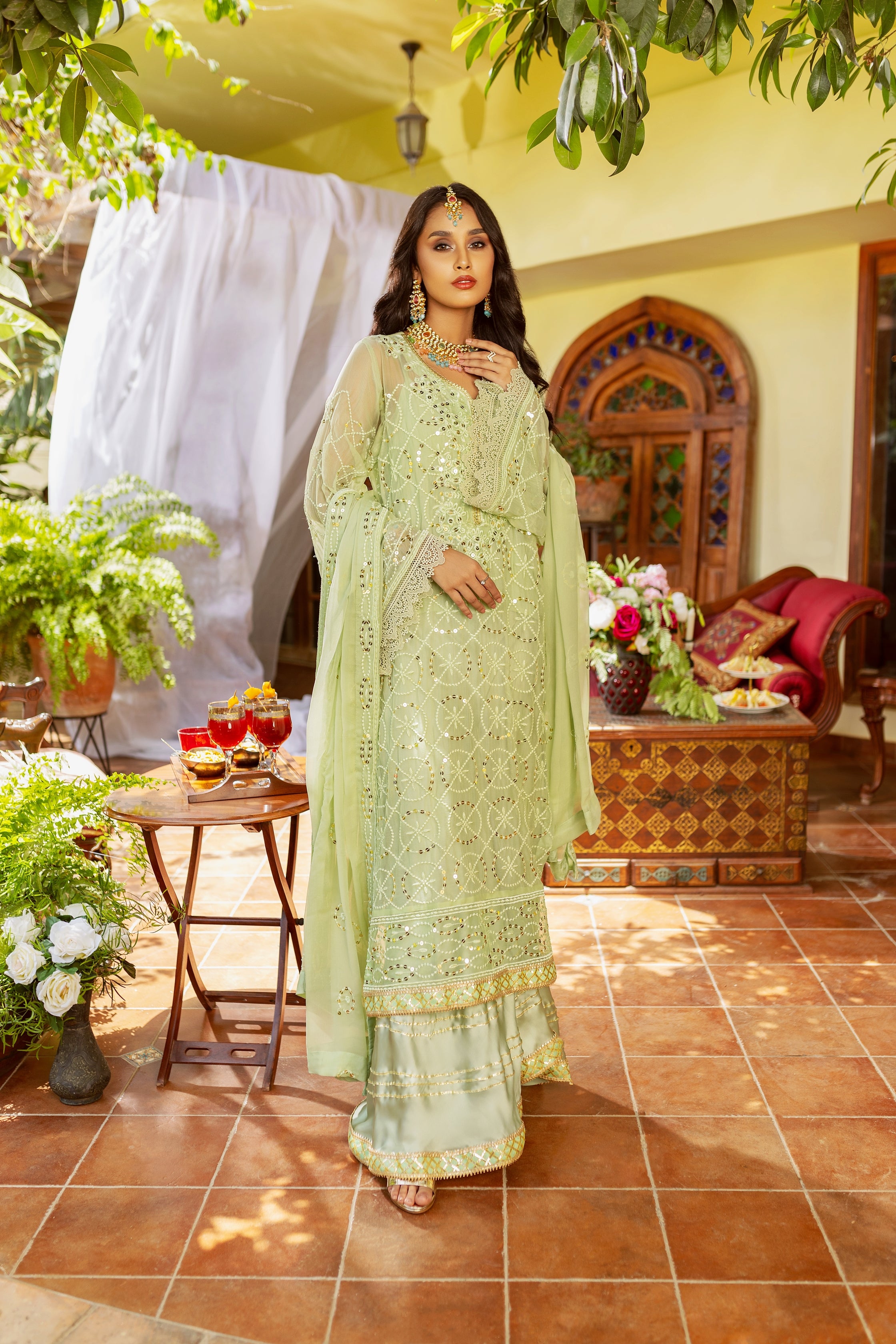 A girl is standing in chiffon embroided suit with silk trouser.