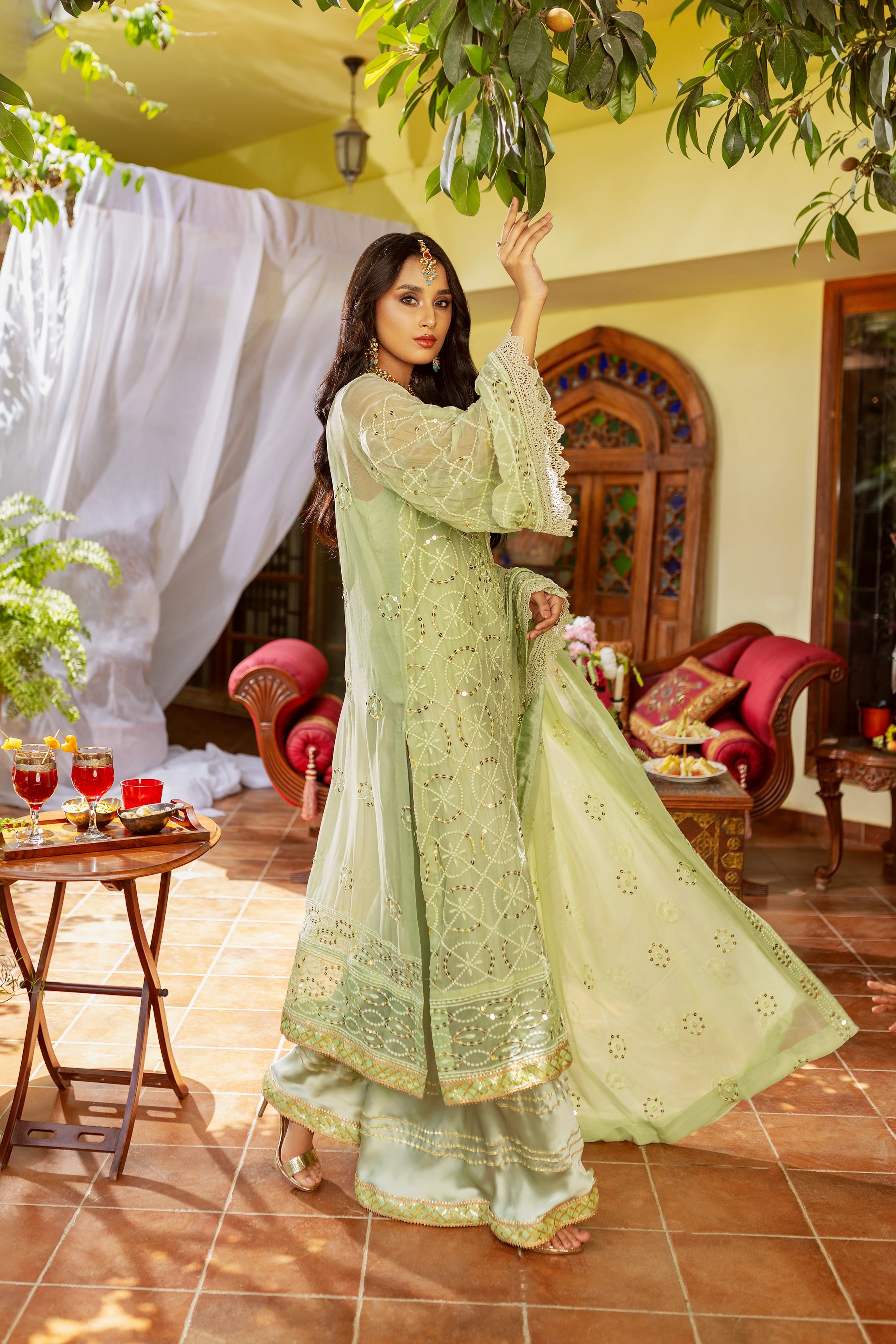 A girl is standing in Light color chiffon suit outside area of a house.