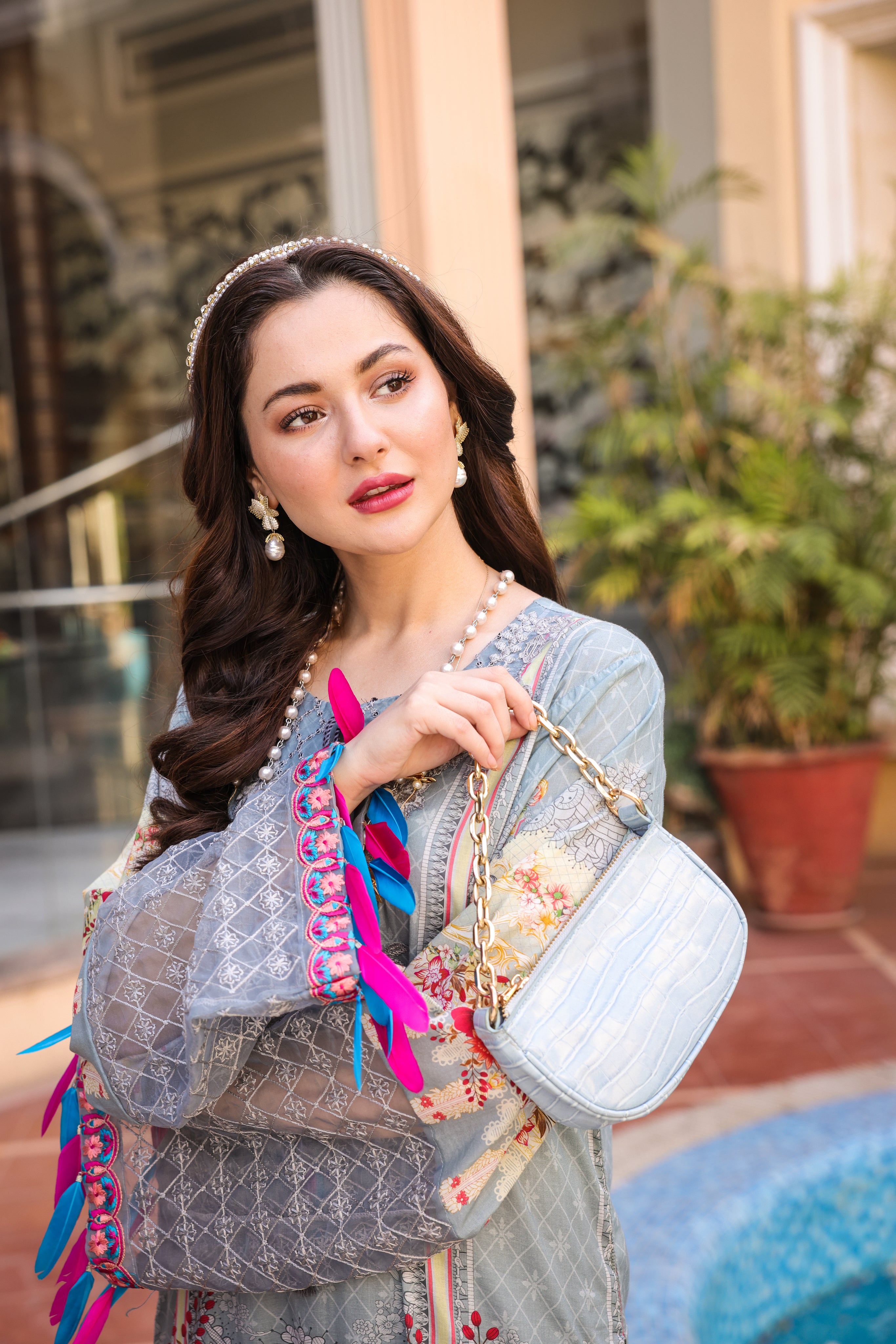 A female model wearing a gry colour embroidered suit with holding a bag in her hand.